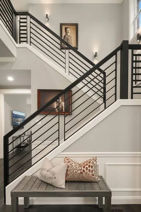 Black horizontal bar stair railing in a double height entrance hall, fabricated by Al Taher Group